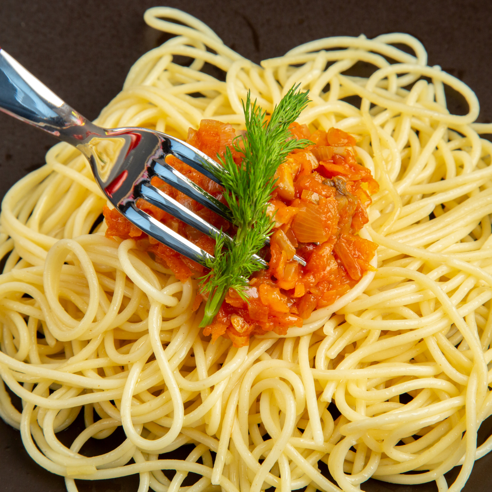 top-close-view-spaghetti-with-sauce-on-plate-fork-on-black-table