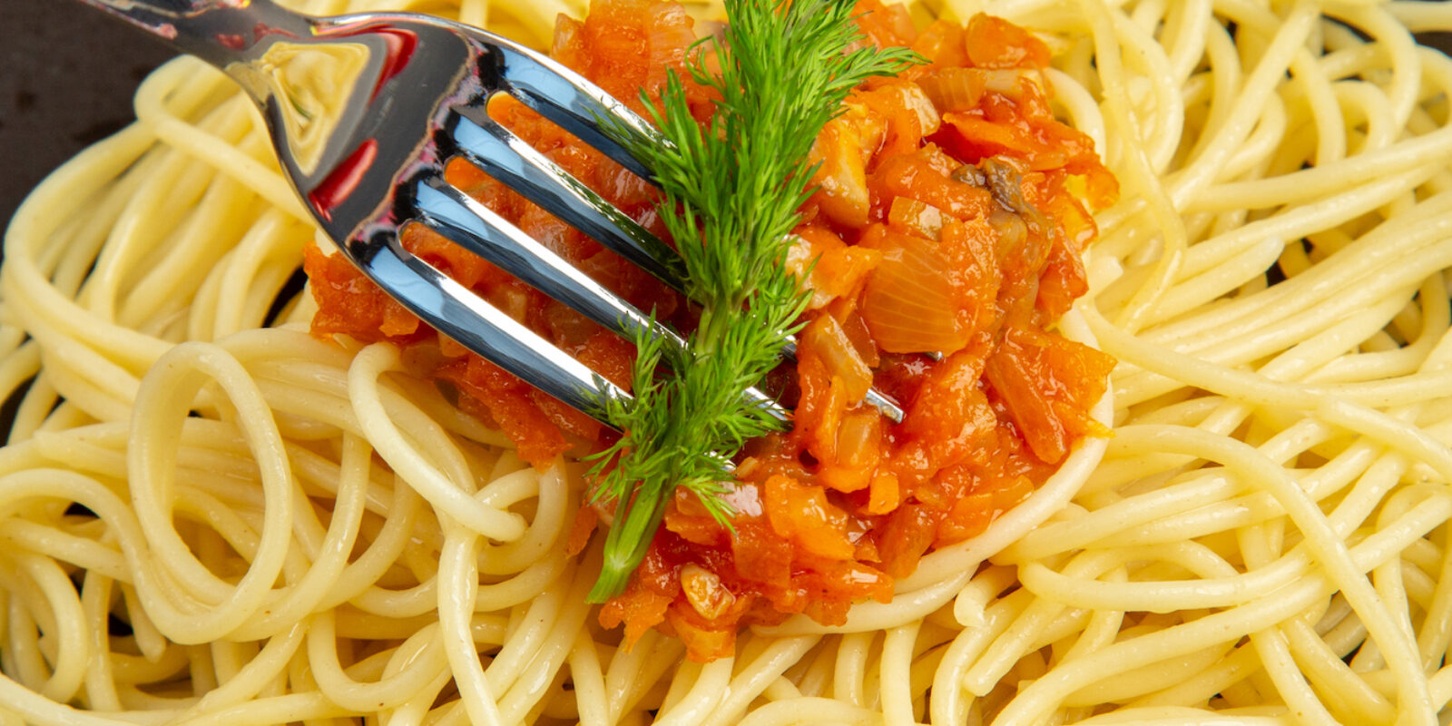 top-close-view-spaghetti-with-sauce-on-plate-fork-on-black-table